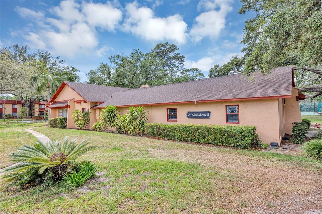 A tan, single-story office and clubhouse building sits on a grassy lot with mature trees — 2864 N POWERS DRIVE UNIT 150, ORLANDO, FL