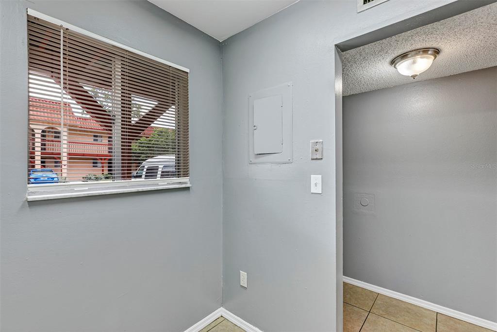 A gray-walled room features a window with blinds, a breaker panel, and a doorway — 2864 N POWERS DRIVE UNIT 150, ORLANDO, FL