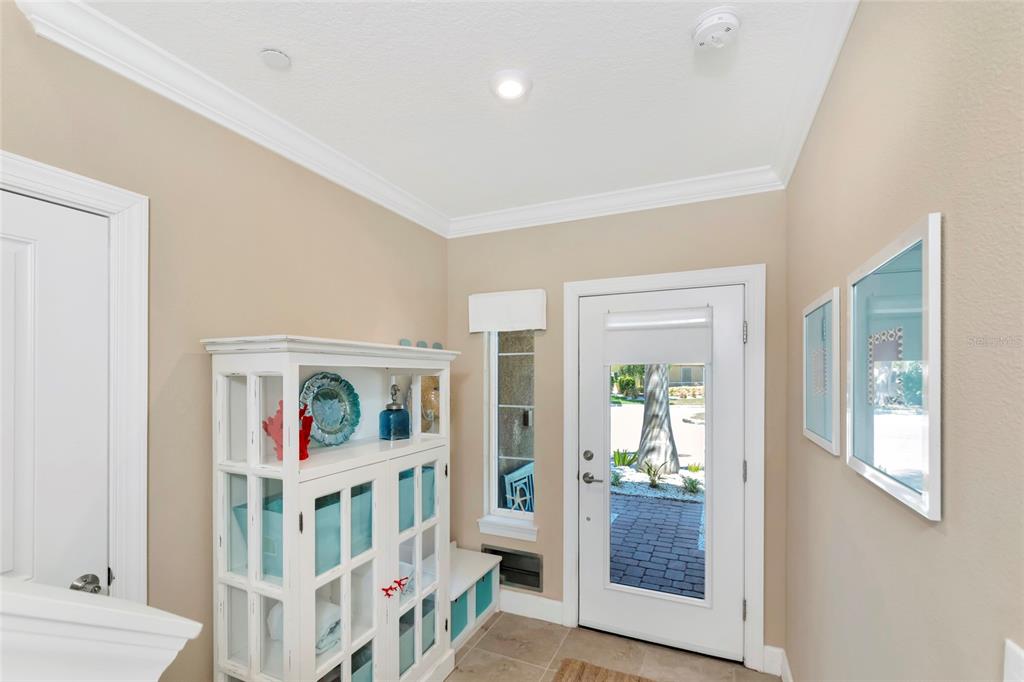 An entryway features a white cabinet, a glass-paneled door, and beige walls with crown molding — 5589 CANNES CIRCLE UNIT 4-102, SARASOTA, FL