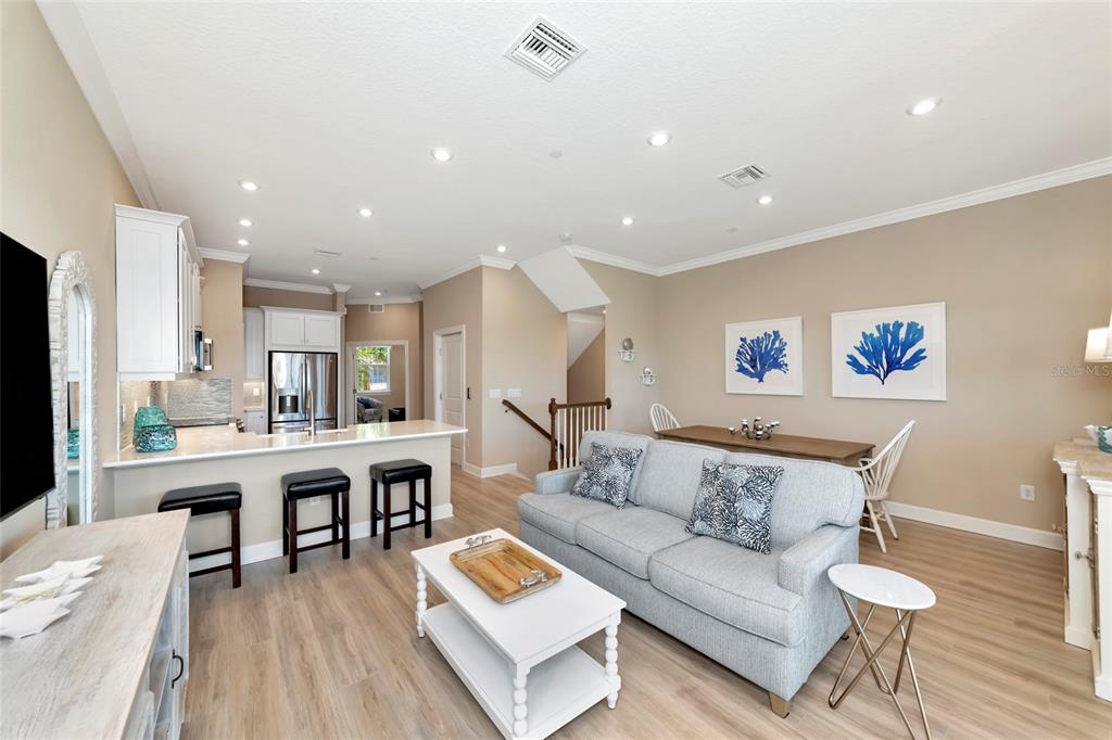 An open-concept living room and kitchen featuring a light gray sofa, breakfast bar, and dining area — 5589 CANNES CIRCLE UNIT 4-102, SARASOTA, FL