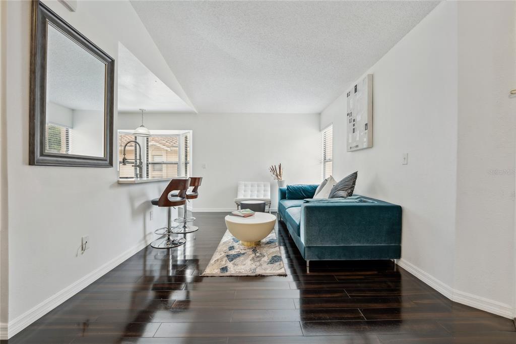 A living room features dark wood floors, a blue velvet sofa, and a breakfast bar — 7667 SUGAR BEND DRIVE UNIT 7667, ORLANDO, FL