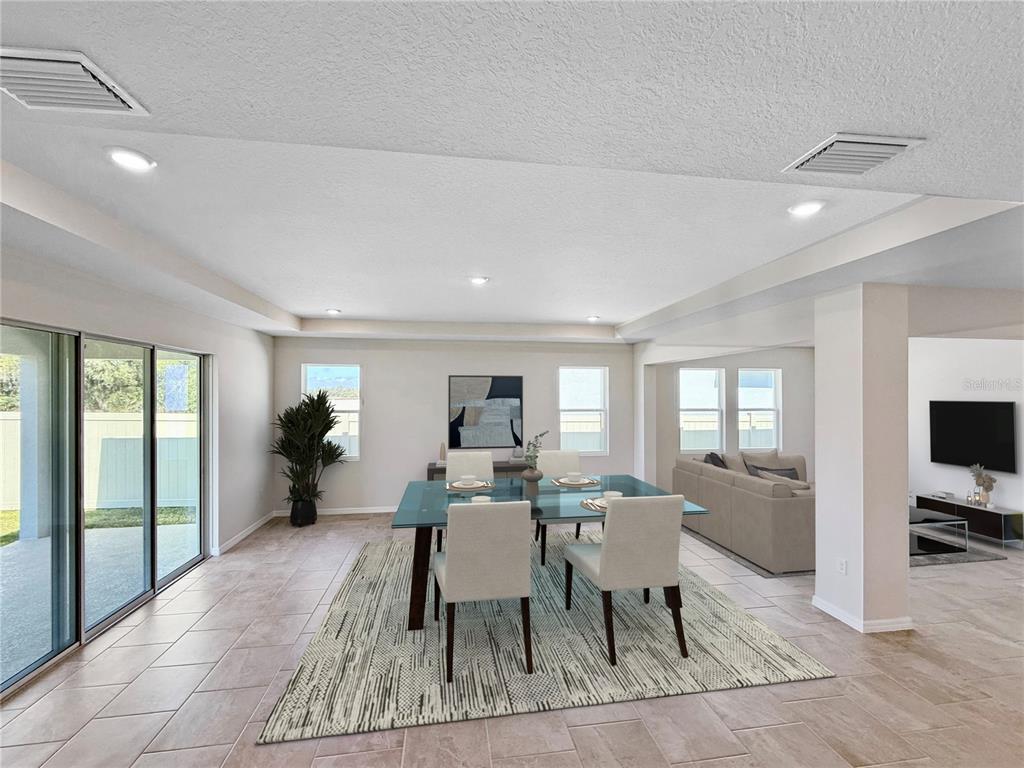 A dining area with a glass table and chairs sits on a rug near a living room — 10471 BRIDGEGATE HEIGHTS LOOP, SAN ANTONIO, FL