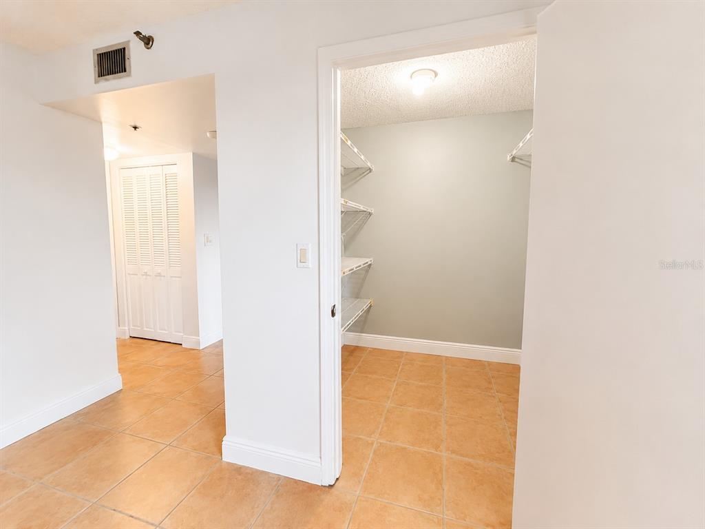 A room with tile flooring and white walls features a walk-in closet with shelving — 1201 S OCEAN DRIVE UNIT 314S, HOLLYWOOD, FL