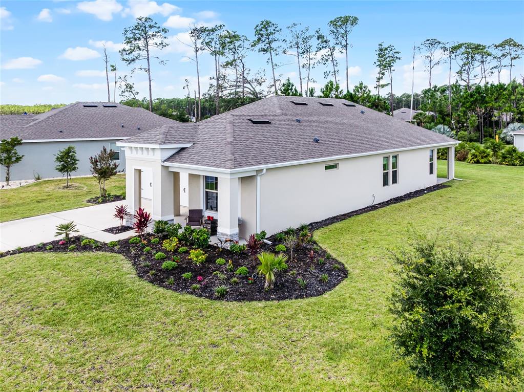 An exterior view of a single-story house with a landscaped garden and a paved driveway — 2892 MONAGHAN DRIVE, ORMOND BEACH, FL