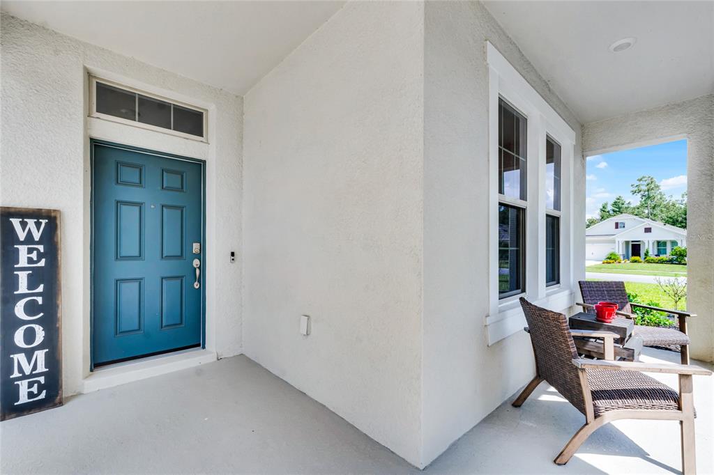 A covered front porch features a blue door, a welcome sign, and two wicker chairs — 2892 MONAGHAN DRIVE, ORMOND BEACH, FL