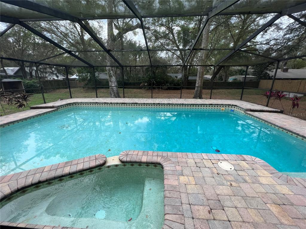A screened-in swimming pool with a spa and brick paver deck in a backyard — 1101 OAKRIDGE MANOR DRIVE, BRANDON, FL