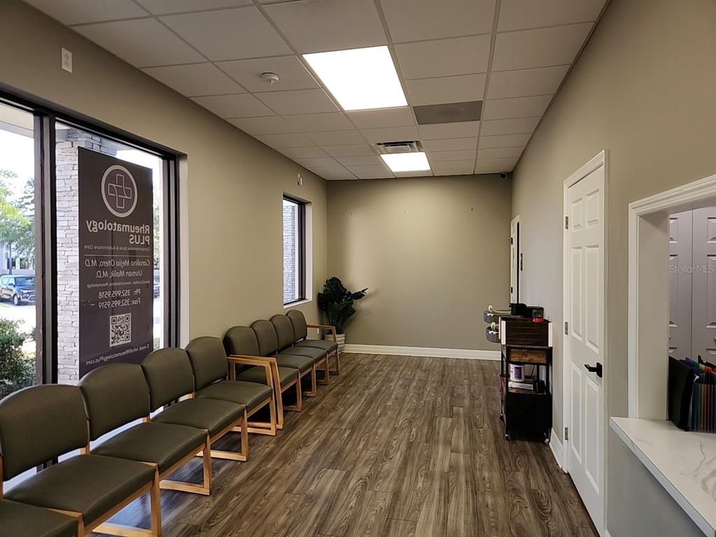A waiting room features rows of chairs, wood-look flooring, and a window with signage — 3721 S US HIGHWAY 27 UNIT B, CLERMONT, FL