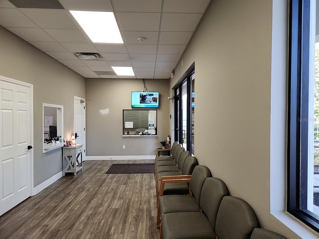 A waiting room features wood-look flooring, rows of chairs, a reception window, and a television — 3721 S US HIGHWAY 27 UNIT B, CLERMONT, FL