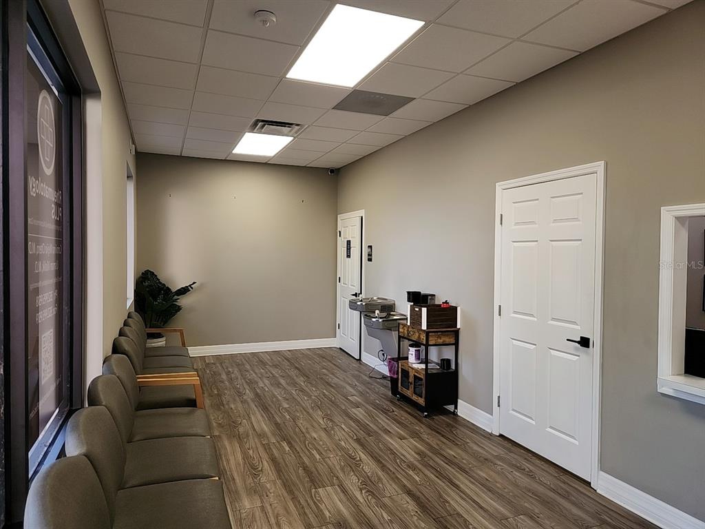 A waiting room features gray walls, wood-look flooring, a row of chairs, and a water fountain — 3721 S US HIGHWAY 27 UNIT B, CLERMONT, FL