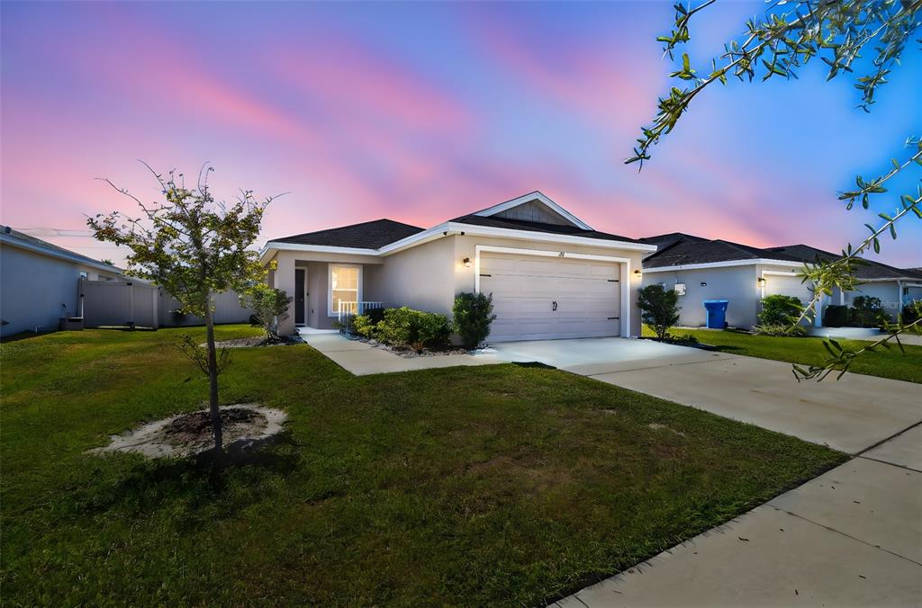 A single-story suburban house with a two-car garage and a lawn at sunset — 114 EAGLE SUMMIT DRIVE, RUSKIN, FL