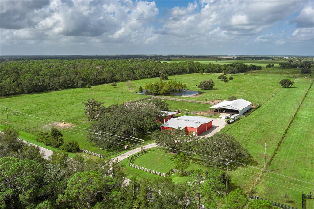 A covered concrete patio runs alongside a red metal building with a hammock and chairs — 1126 COUNTY ROAD 665, ONA, FL