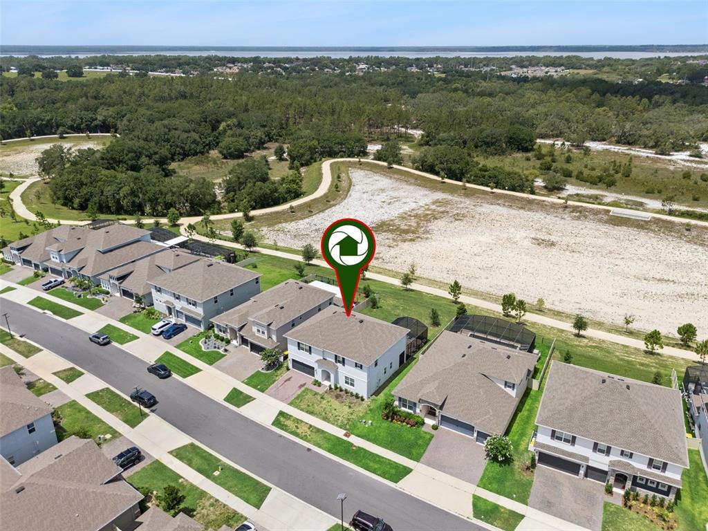 An aerial view shows a suburban house with a backyard facing an open sandy area — 4395 RENLY LANE, CLERMONT, FL