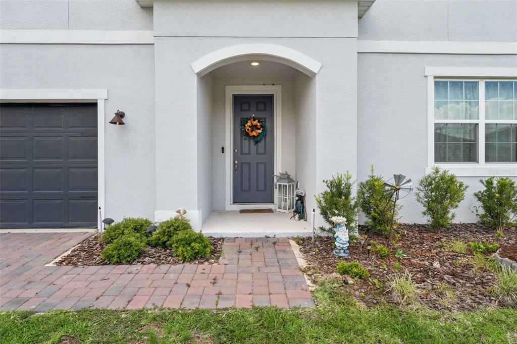 A gray front door with a wreath sits under an arched entryway beside a garage — 4395 RENLY LANE, CLERMONT, FL