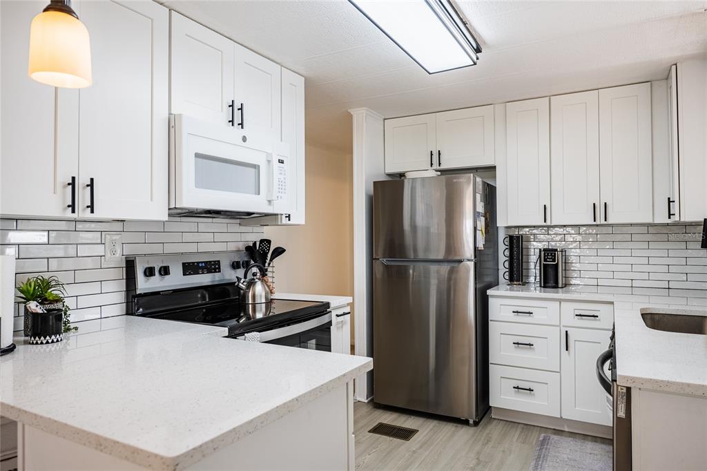 A light-colored mobile home with a carport and a large tree in the front yard — 36749 JODI AVENUE, ZEPHYRHILLS, FL