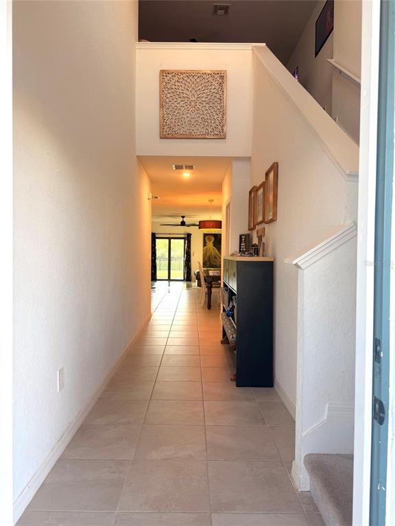 A tiled entryway leads to a hallway with a staircase and a view of the dining area — 9116 TEQUILA SUNRISE DRIVE, SARASOTA, FL