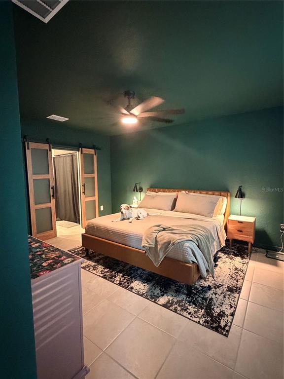 A bedroom features dark green walls, a platform bed, sliding barn doors, and tile flooring — 9116 TEQUILA SUNRISE DRIVE, SARASOTA, FL