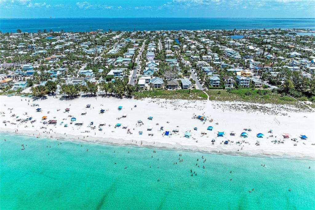 An aerial view of a white sand beach with umbrellas and a coastal residential neighborhood — 101 PALM AVENUE UNIT 1, ANNA MARIA, FL