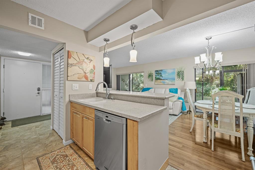 A kitchen with light wood cabinets and a stainless steel dishwasher overlooks a dining area — 37 ALCIRA COURT UNIT 37, ST AUGUSTINE, FL