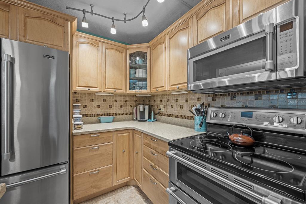 A kitchen features light wood cabinets, stainless steel appliances, and a tiled backsplash — 37 ALCIRA COURT UNIT 37, ST AUGUSTINE, FL