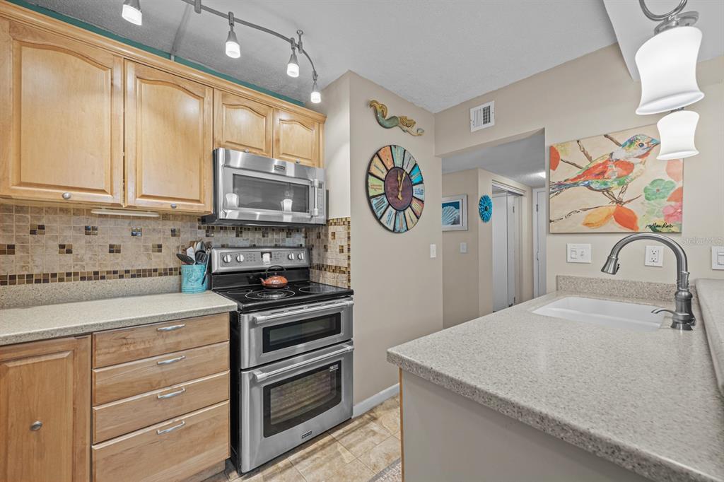 A kitchen features light wood cabinets, stainless steel appliances, a tiled backsplash, and granite countertops — 37 ALCIRA COURT UNIT 37, ST AUGUSTINE, FL