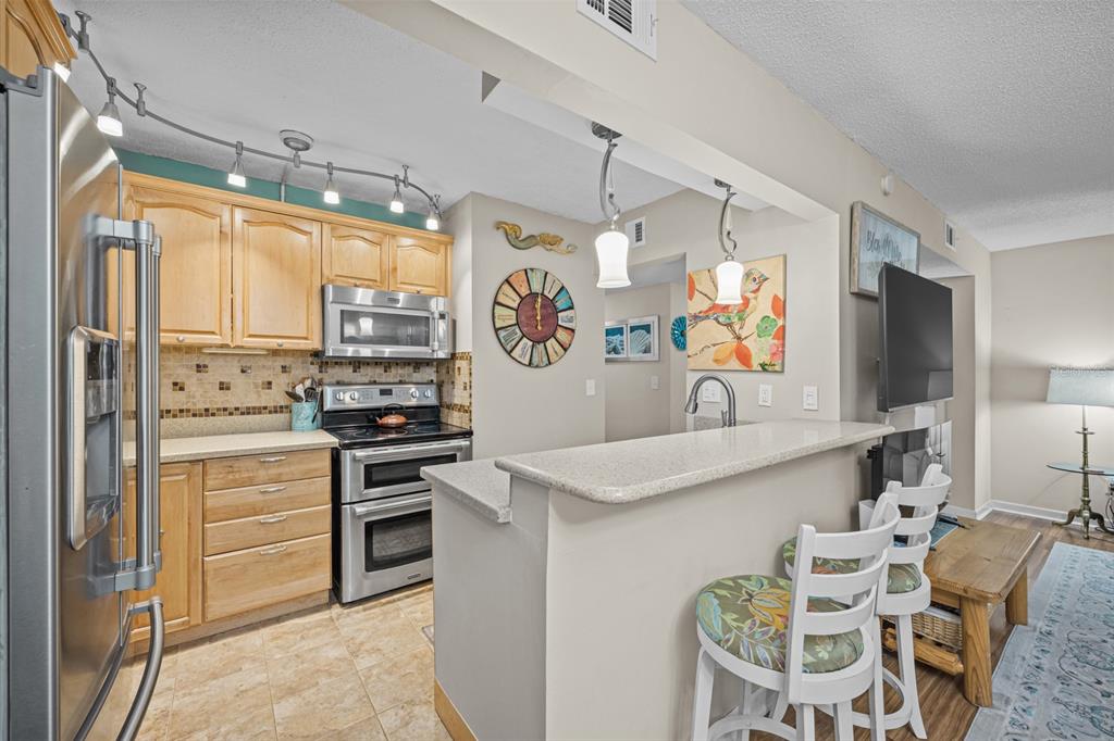 A kitchen with light wood cabinets, stainless steel appliances, and a breakfast bar with stools — 37 ALCIRA COURT UNIT 37, ST AUGUSTINE, FL