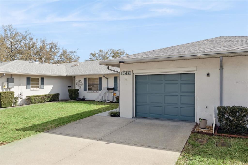 A single-story house with a blue garage door, white stucco walls, and a front lawn — 1581 OAKVIEW CIRCLE SE, WINTER HAVEN, FL