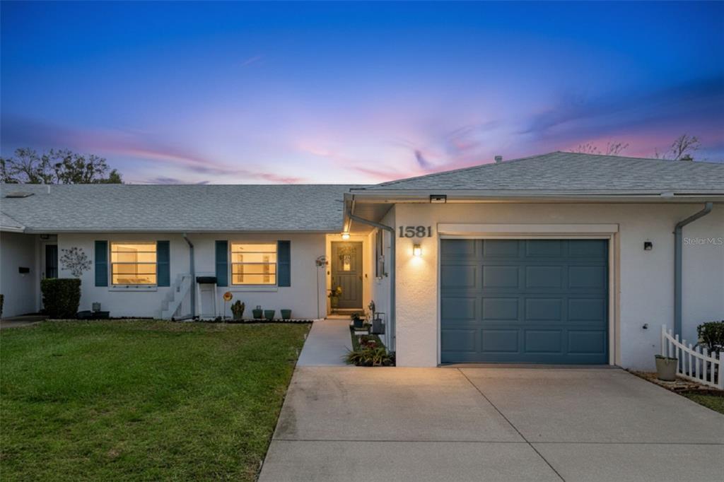 A single-story house with a white exterior, a blue garage door, and a concrete driveway — 1581 OAKVIEW CIRCLE SE, WINTER HAVEN, FL