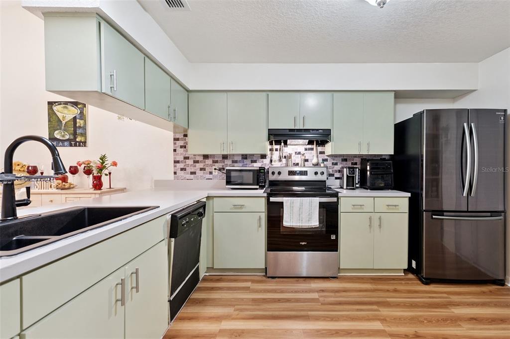 A bedroom features wood-look flooring, a dark wood bed frame, and a light green accent wall — 1581 OAKVIEW CIRCLE SE, WINTER HAVEN, FL