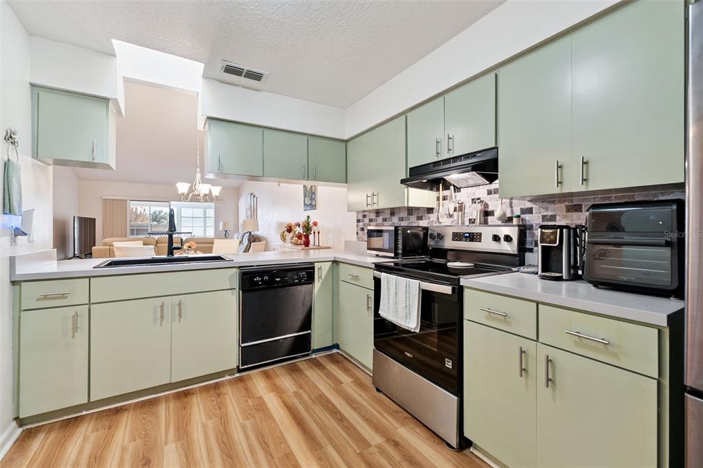A bedroom features wood-look flooring, a ceiling fan, a dresser with a mirror, and an ensuite — 1581 OAKVIEW CIRCLE SE, WINTER HAVEN, FL