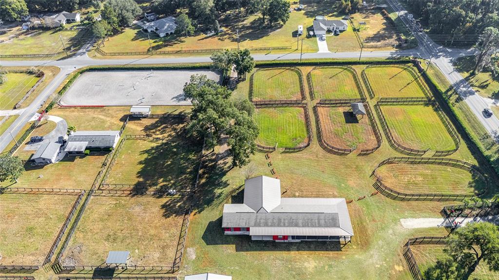 An aerial view shows a horse farm with a barn, paddocks, and a riding arena — 2 COUNT FLEET DRIVE, OCALA, FL