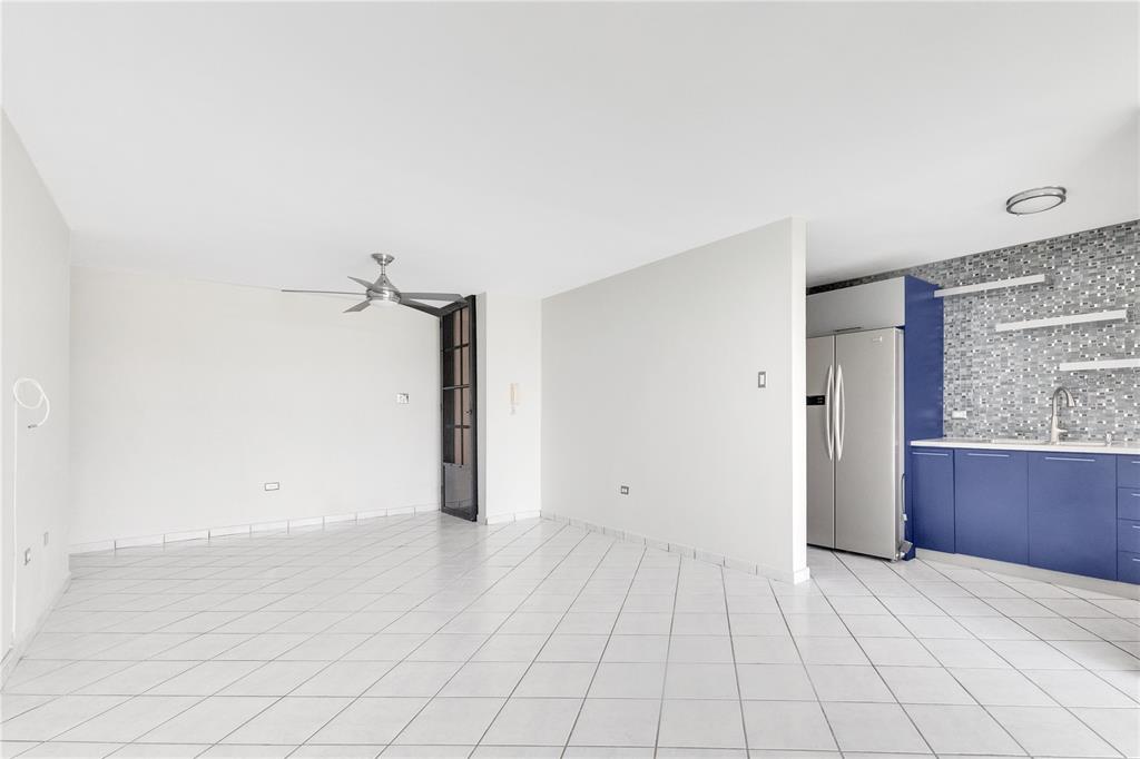 An open-concept living area features white tile flooring, a ceiling fan, and a blue kitchen — AVE. TRIOVEGABAJEÑO COND. TORRE VISTA APT. 1504, VEGA BAJA, PR