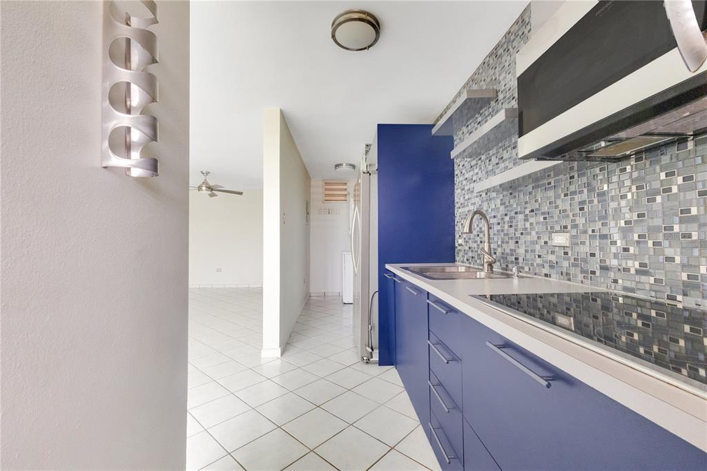 A kitchen with blue cabinets, a mosaic tile backsplash, and white tile flooring — AVE. TRIOVEGABAJEÑO COND. TORRE VISTA APT. 1504, VEGA BAJA, PR