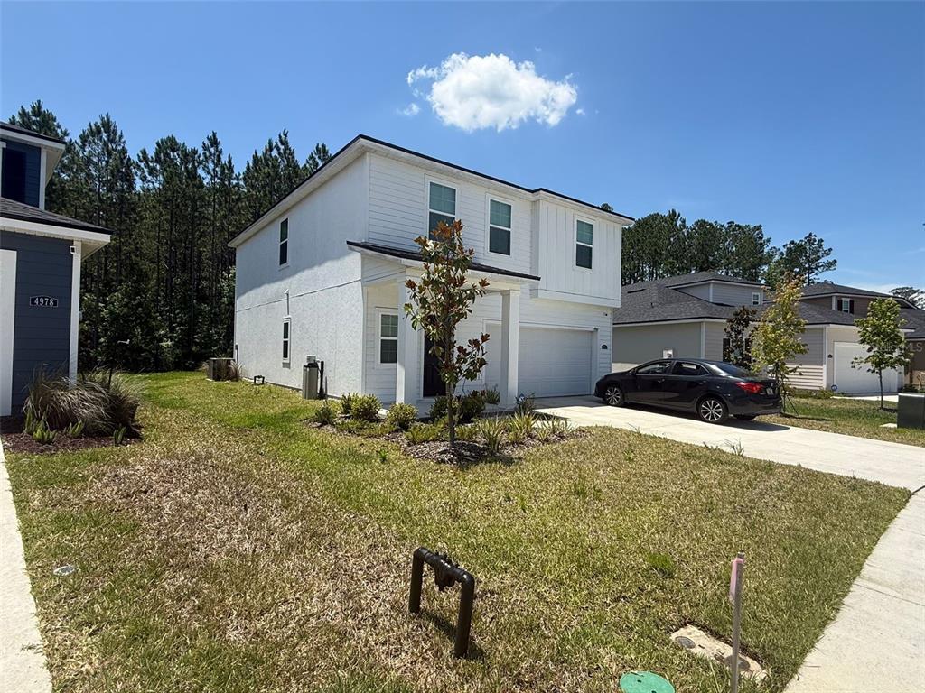 A two-story white house with a garage and a front yard under a blue sky — 4984 BIG PINE DRIVE, JACKSONVILLE, FL