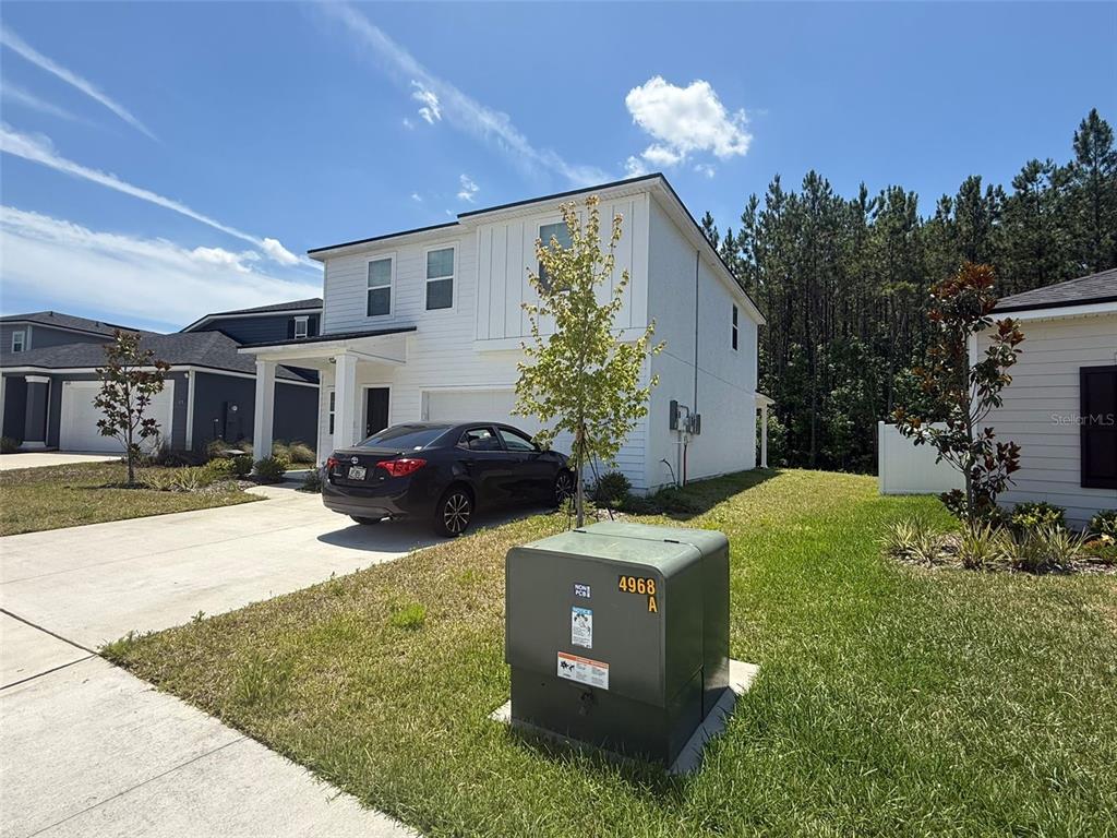 A two-story white house with a driveway and a green utility box in the foreground — 4984 BIG PINE DRIVE, JACKSONVILLE, FL