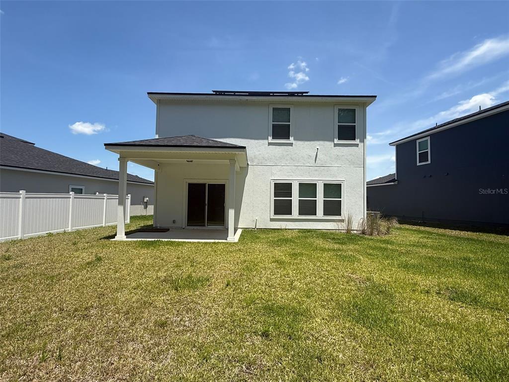 The rear exterior of a two-story house features a covered patio and a fenced yard — 4984 BIG PINE DRIVE, JACKSONVILLE, FL