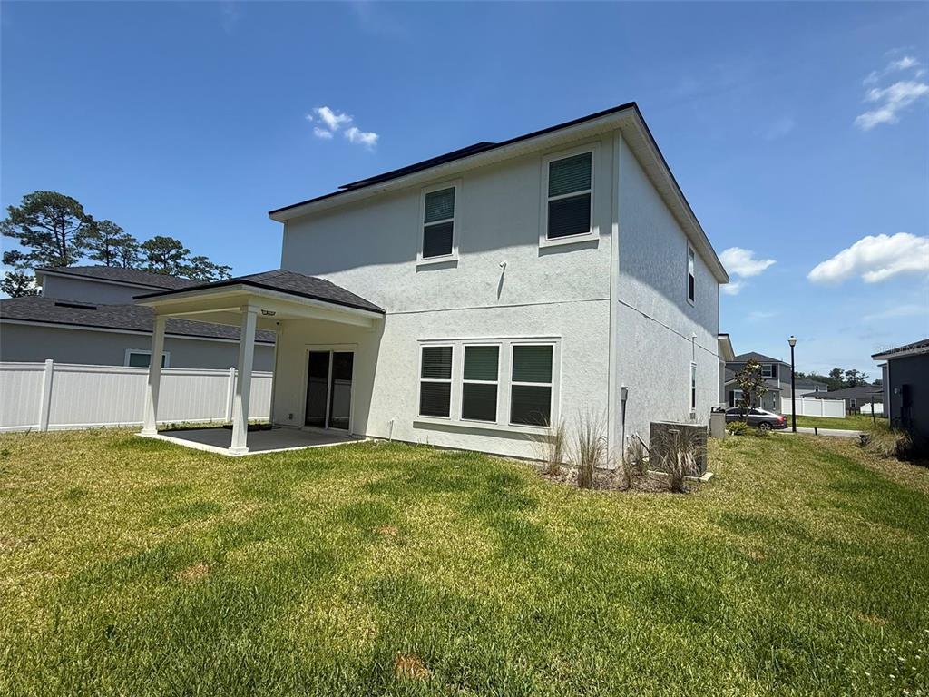 The rear exterior of a two-story house features a covered patio and a fenced yard — 4984 BIG PINE DRIVE, JACKSONVILLE, FL
