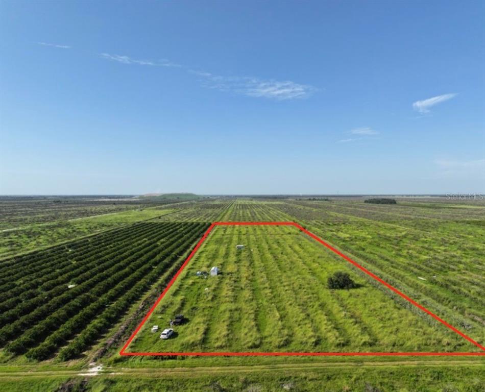 An aerial view shows a rectangular plot of land outlined in red amidst agricultural fields — NE HWY 70, ARCADIA, FL