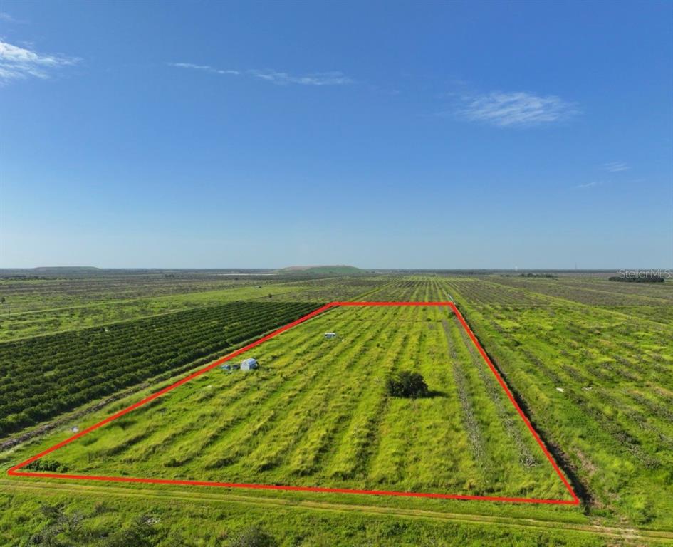 An aerial view shows a rectangular plot of land outlined in red amidst agricultural fields — NE HWY 70, ARCADIA, FL
