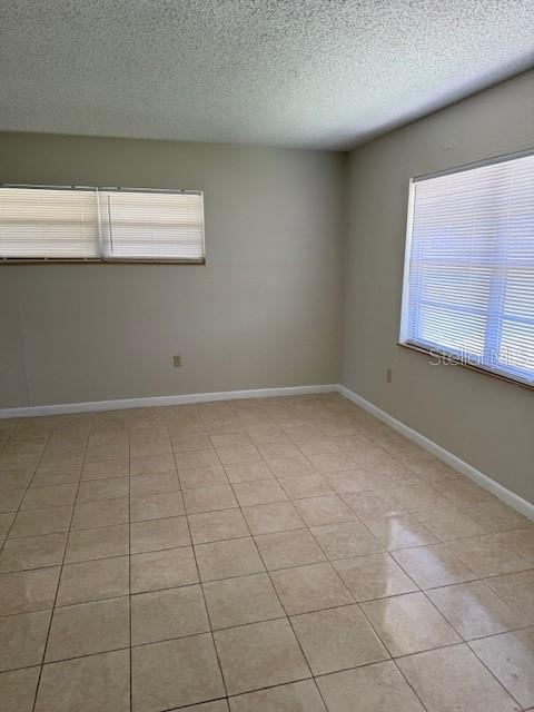 An empty room features beige walls, light-colored tile flooring, and two windows with blinds — 217 ALDO DRIVE, BABSON PARK, FL