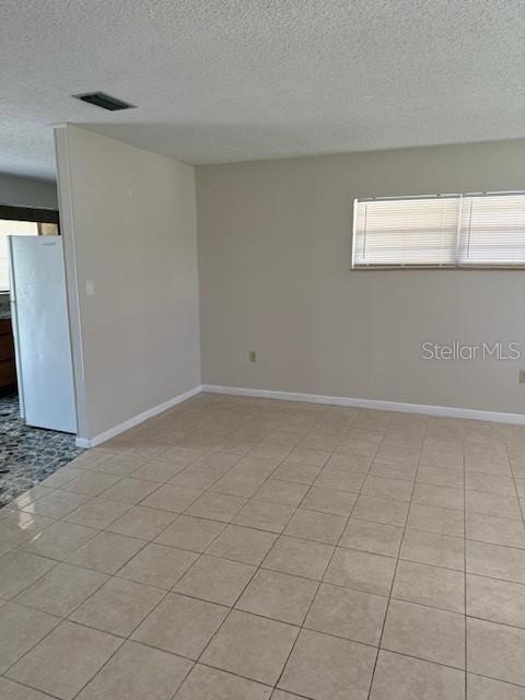 An interior view of a room with light-colored tile flooring, beige walls, and a window — 217 ALDO DRIVE, BABSON PARK, FL