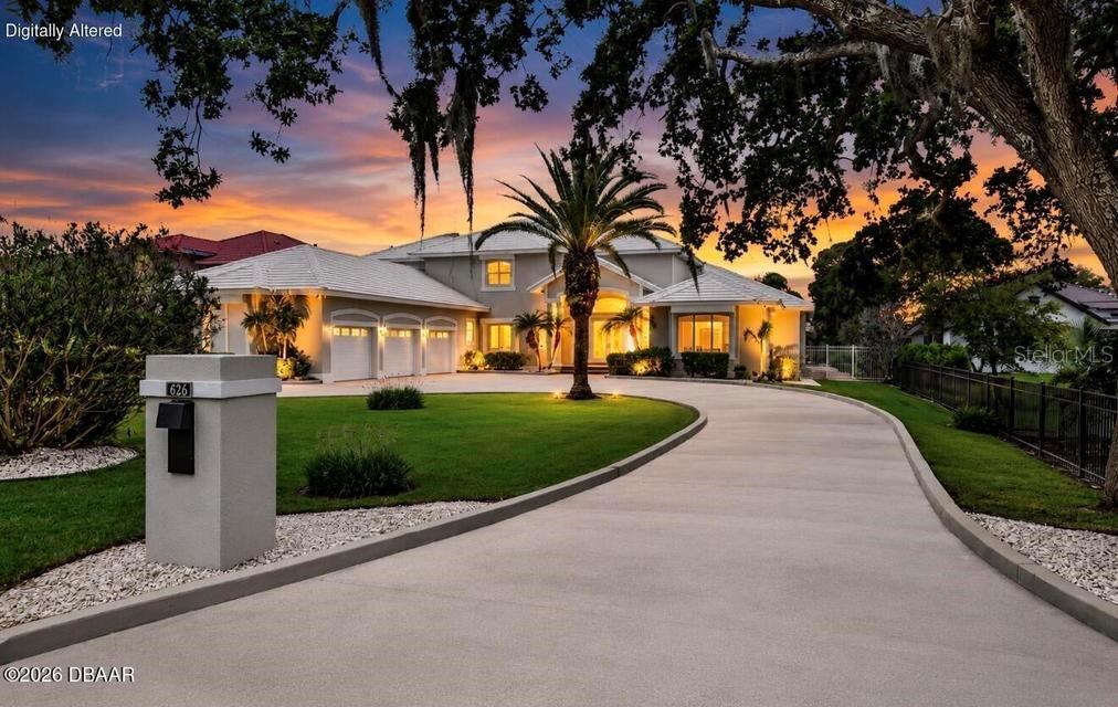 A large single-story house with a curved driveway and a prominent palm tree at sunset — 626 RIVERSIDE DRIVE, ORMOND BEACH, FL