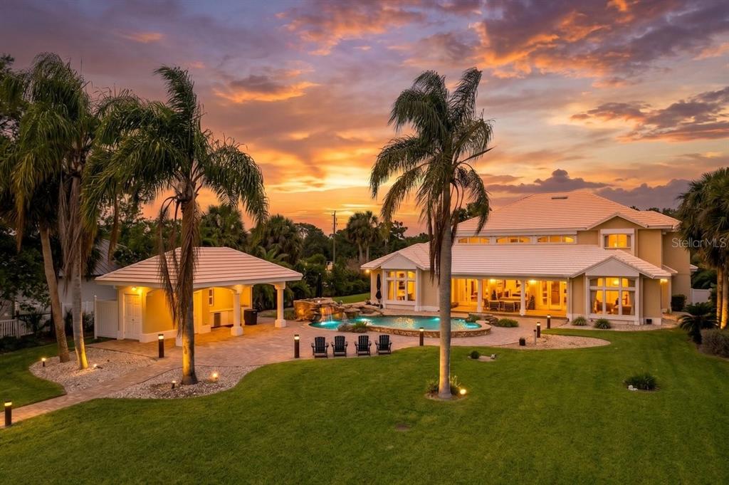 A large house with a pool, patio, and palm trees at sunset — 626 RIVERSIDE DRIVE, ORMOND BEACH, FL