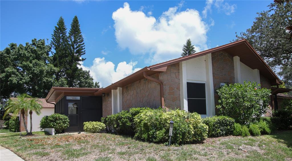 A single-story house with stone veneer siding, a dark entryway, and surrounding landscaping — 2360 SHELLY DRIVE UNIT B, PALM HARBOR, FL