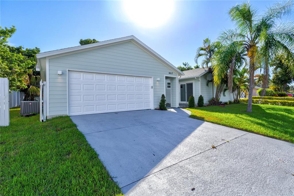 A light green house with a white garage door and a concrete driveway — 6617 MAUNA LOA BOULEVARD, SARASOTA, FL