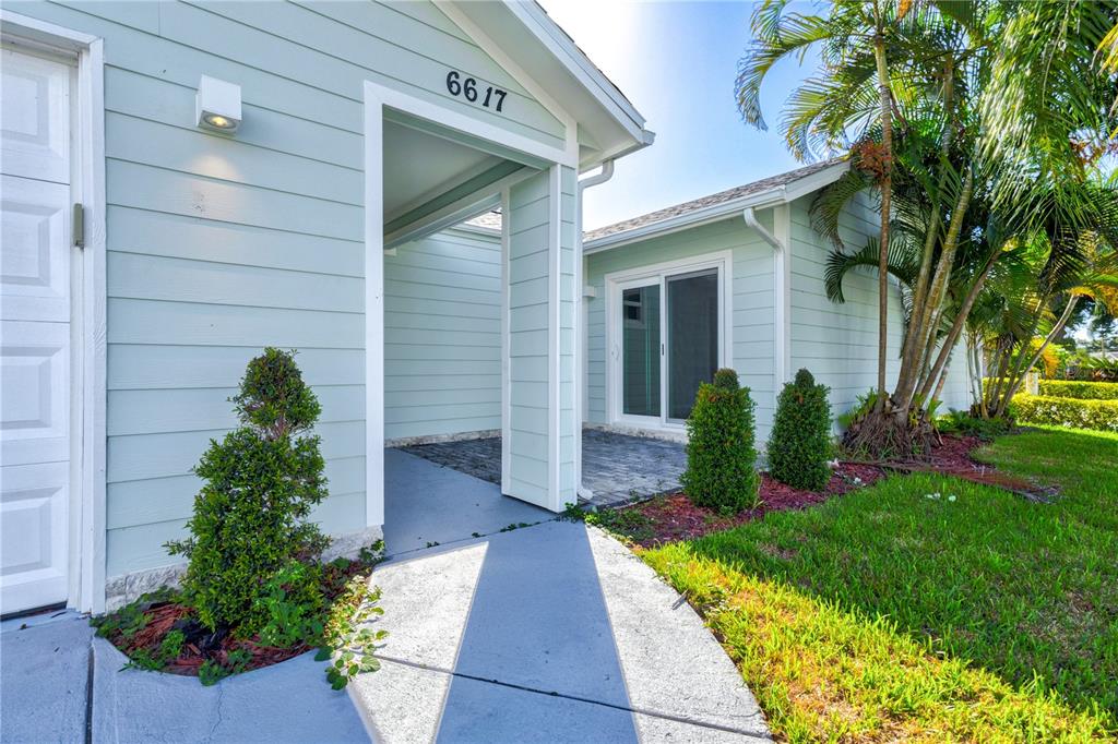 A light blue house exterior features a covered entryway, a garage, and a paved patio — 6617 MAUNA LOA BOULEVARD, SARASOTA, FL