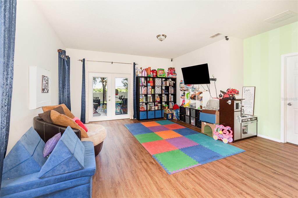 A playroom with wood-look flooring, a colorful foam mat, a bookshelf, and a television — 30308 CHEVAL STREET, MOUNT DORA, FL