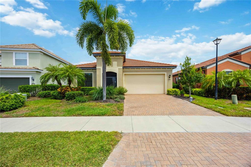 A single-story house with a beige stucco exterior, a tiled roof, and a paved driveway — 23781 WAVERLY CIRCLE, VENICE, FL