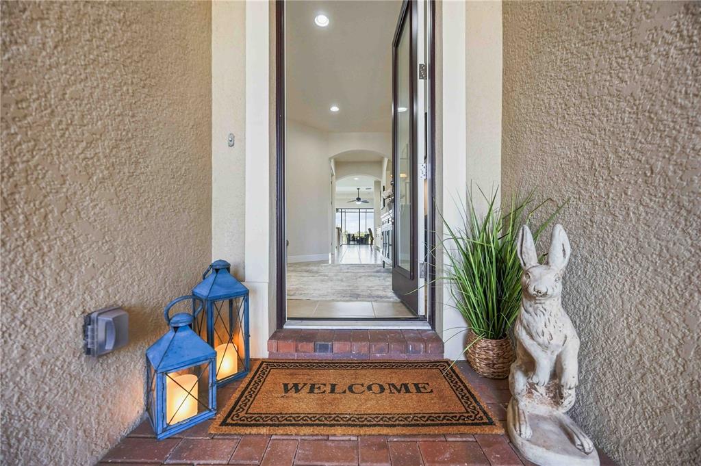 A front entryway features a welcome mat, two blue lanterns, and a rabbit statue — 23781 WAVERLY CIRCLE, VENICE, FL