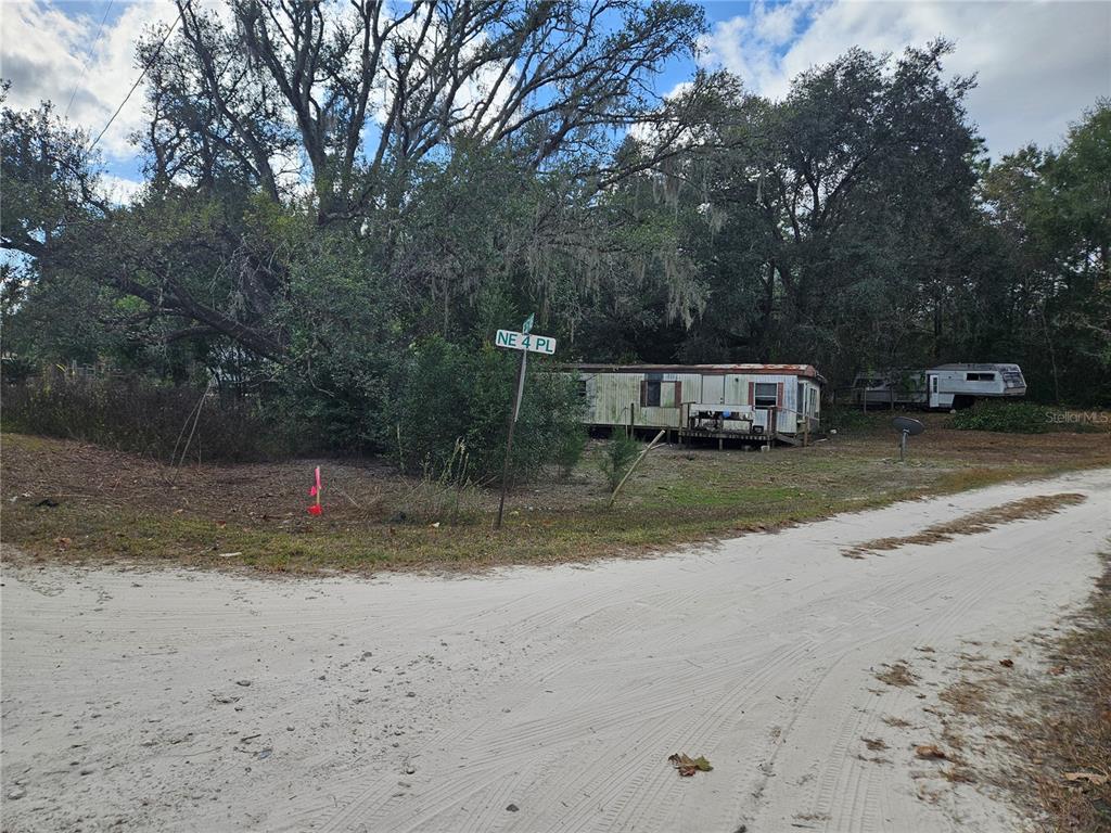 A weathered mobile home sits on a dirt road near a street sign — 15950 NE 4TH PLACE, WILLISTON, FL