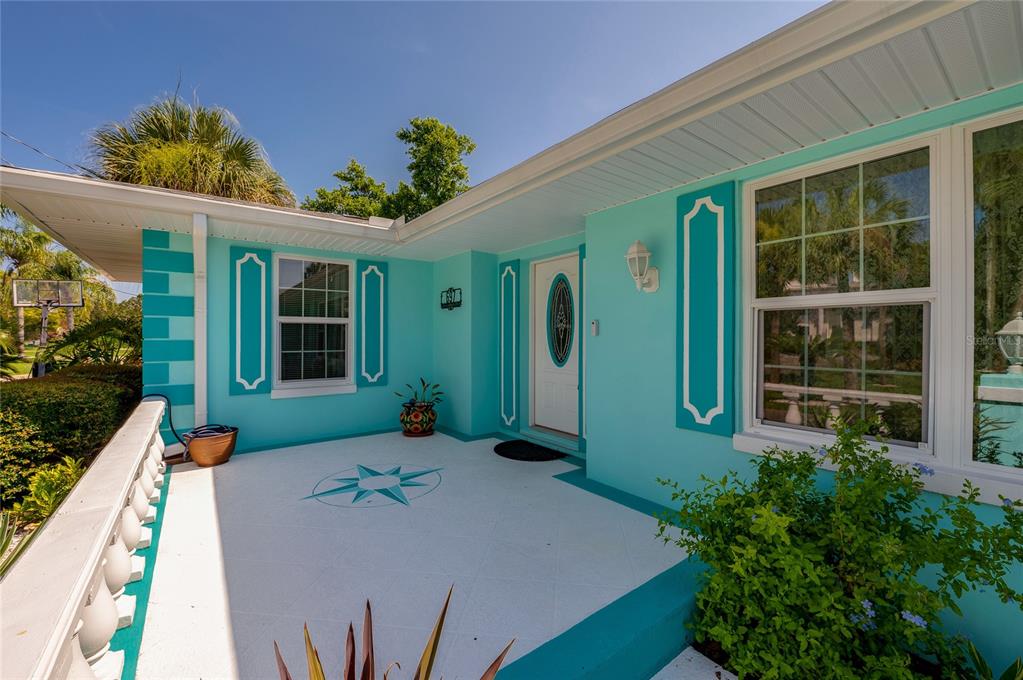 A bright turquoise house exterior features white window shutters, a stone walkway, and a balustrade — 697 JOHN ANDERSON DRIVE, ORMOND BEACH, FL